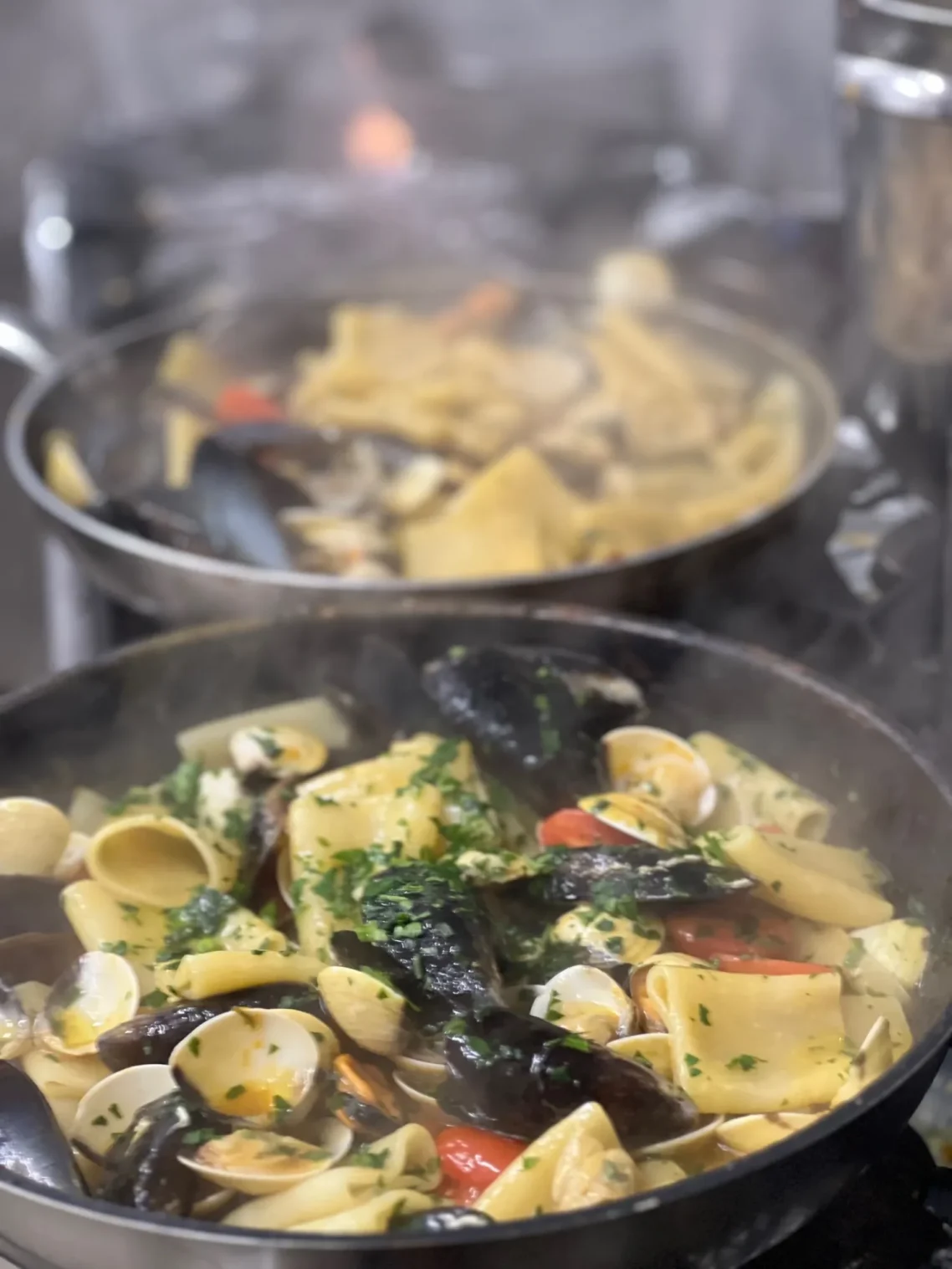 Pasta mit Meeresfrüchten in Zubereitung Frische Paccheri mit Muscheln und Meeresfrüchten in der Pfanne beim Kochen