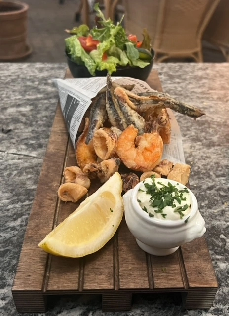 Frittierte Meeresfrüchte mit Dip Knusprig frittierter Fisch und Garnelen mit Zitrone und Dip auf Holzbrett serviert
